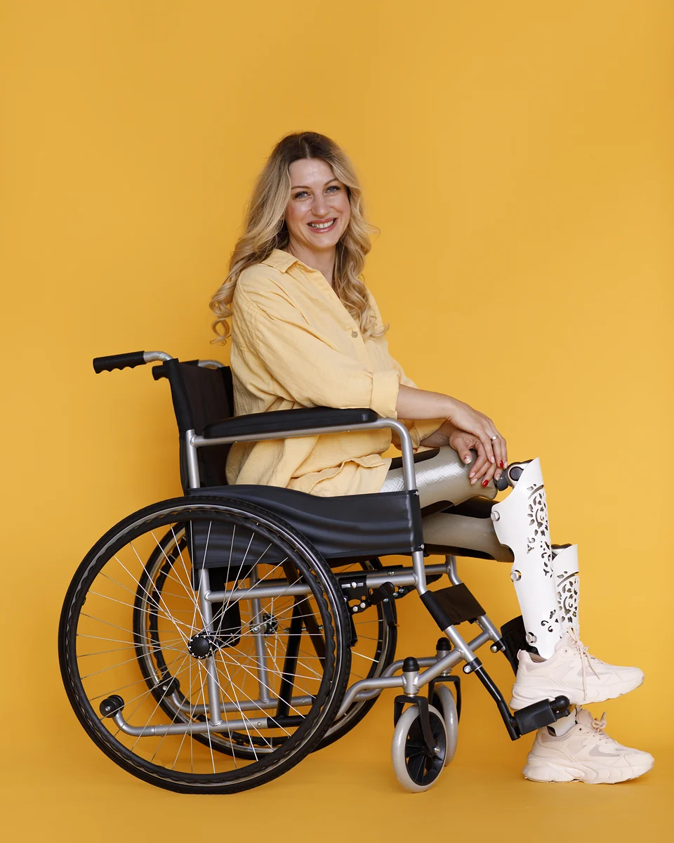 Jovem sorridente com prótese na perna sentada em cadeira de rodas manual — cadeira de rodas pós-cirúrgica em Engenheiro Coelho